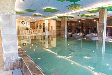 Großer Indoor-Pool mit Kinderspielbereich und Liegen im Familienhotel Landhaus zur Ohe im Bayerischen Wald.