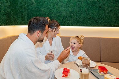 Familie sitzt mit Bademämteln im Bistro des Familienhotels Schreinerhof im Bayerischen Wald.