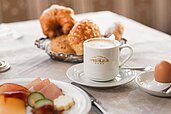 Gedeckter Tisch mit Gebäck, Obst, Ei und Kaffee im Familienhotel Adler Familien- & Wohlfühlhotel in Tirol.