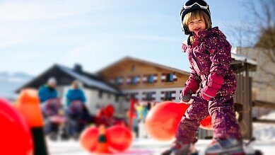 Skilehrerin bringt zwei kleinen Mädchen auf dem Zauberteppich des Familienhotels Amiamo das Skifahren bei.