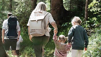 Familie wandert durch den Wald im Familienurlaub in Tirol