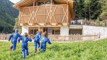 Kinder toben in der Wiese auf dem Gelände des Familienhotels Huber in Südtirol