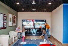 Familie mit zwei Kindern spielt an einer interaktiven iWall-Spielewand im AIGO Welcome Family Bereich.