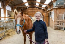 Mädchen führt ein Pony im Stall des Familienhotel Ottonenhof.