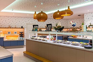 Blick auf das vielfältige und farbenfrohe Buffet im Restaurant des Familienhotels Deichkrone an der Nordsee, mit einer Auswahl an frischen Salaten, Aufschnitt, Brot und warmen Speisen, präsentiert auf einem ansprechend gestalteten Buffettisch.