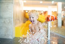 Das Kleinkind hat große freude im Kinderbecken des Familiehotels Landhaus zur Ohe im Bayerischen Wald.