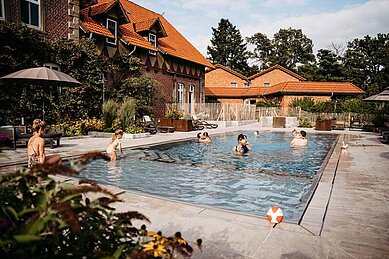 Familien planschen im Außenpool des Familienhotels Landhaus Averbeck in der Lüneburger Heide.