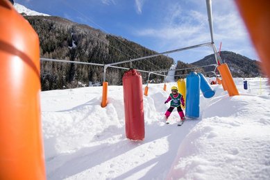 Kind fährt im Rahmen des Skikurses vom Familienhotel Huber auf Skiern durch den Parcours 