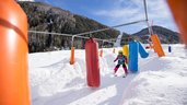 Kind fährt im Rahmen des Skikurses vom Familienhotel Huber auf Skiern durch den Parcours 