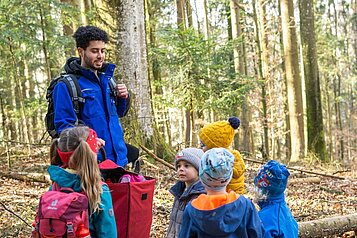 Einige Kinder und ein Kinderbetreuer im Outdoorclub im Wald im Landhaus zur Ohe im Bayerischen Wald. 