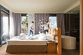 Zwei Kinder machen eine Kissenschlacht auf dem Bett in der Luxuxsuite im Familienhotel Ulrichshof im Bayerischen Wald