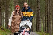 Mutter und Vater bei einer kinderwagengerechten Wanderung durch den Wald nahe des Familotels Kaiserhof in Berwang