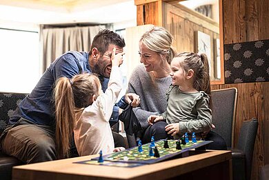 Eine Familie beim Brettspiel im Last-Minute Familienurlaub in einem Familotel