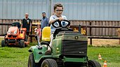 Junge sitzt auf einem kleinen Traktor auf dem Gelände des Bernsteinreiter Schlossresorts