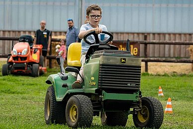 Junge sitzt auf einem kleinen Traktor auf dem Gelände des Bernsteinreiter Schlossresorts