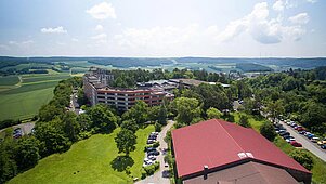 Außenansicht des Familienhotels Sonnenhügel in der Rhön im Sommer. Das Familienhotel ist umgeben von grünen Wiesen und Bäumen.