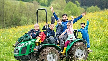 Der Kinderbetreuer des Familienhotels Landhaus zur Ohe fährt mit den Kindern Traktor im Bayerischen Wald.