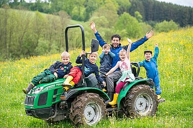 Der Kinderbetreuer des Familienhotels Landhaus zur Ohe fährt mit den Kindern Traktor im Bayerischen Wald.