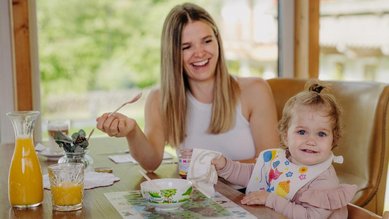 Ein Kleinkind wird am Tisch im Restaurante gefüttert.