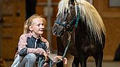 Das Mädchen freut sich das Pony im Elldus Resort Im Erzgebirge auszuführen.