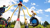 Mehrere Kinder spielen auf dem Outdoor Spielplatz im Familienhotel Lärchenhof in Tirol