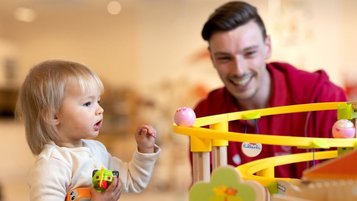 Kinderbetreuer spielt mit einem Kleinkind im Happy-Club des Familienhotels Sonnenpark.