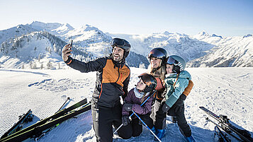 Eine Familie im Winterurlaub in den Bergen macht Fotos von sich.