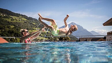 Mutter und Sohn planschen im Infinitypool des Kinderhotels Stefan in Tirol.