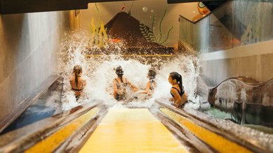 Vier Mädels rutschen auf der Trio-Slide-Rutsche im Alpenhotel Kindl im Stubaital.