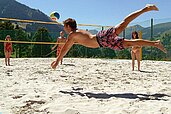 Familie spielt auf dem Volleyballplatz an einem Sommertag Volleyball und genießen den Aufenthalt im Familienhotel Sonngastein in Bad Gastein.