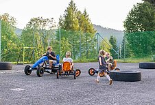 Kinder fahren Go-Karts auf dem Hotelgelände des Familienhotels Alpengasthof Hochegger in Kärnten