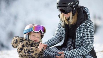 Eine Mutter mit ihrer Tochter im Skianzug im Schnee in der Nähe des Familienhotels Das Bayrischzell in Oberbayern.