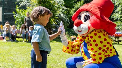 Kleiner Junge gibt Maskottchen Happy ein High Five im Family Club Harz