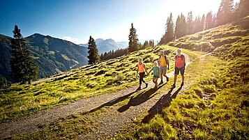 Eine Gastfamilie vom Wellness- & Familienhotel Egger wandert durch die Landschaft in Saalbach Hinterglemm.