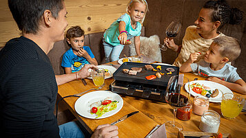 Familie genießt ihr privates Raclette zu Abend im Familienurlaub in den Mons Silva Private Luxury Chalets in Südtirol.