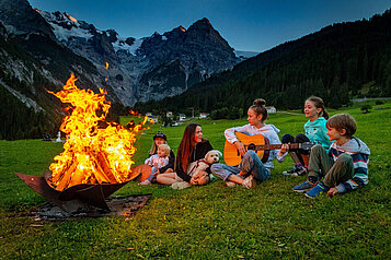 Ein Lagerfeuer mit Kinder die Lieder singen.