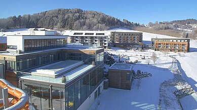 Das Familienhotel Schreinerhof im Bayerischen Wald von außen im Winter mit einer großen Außenanlage und Outdoor-Spielplatz für Kinder.