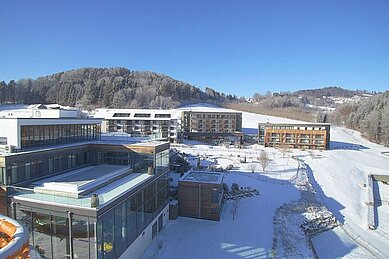 Das Familienhotel Schreinerhof im Bayerischen Wald von außen im Winter mit einer großen Außenanlage und Outdoor-Spielplatz für Kinder.