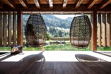 Eltern sitzen im Wellness-Ruhebereich und genießen die Panoramaaussicht vom Familienhotel Alphotel Tyrol Wellness & Family Resort.