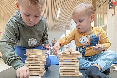 Kinder sitzen in der Kinderbetreuung am Basteltisch und basteln ein Nest mit ihrer Betreuerin im Familienhotel Gorfion in Lichtenstein.