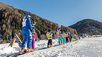 Kinder beim Skifahren in der Skischule im Familienhotel Huber in Südtirol.