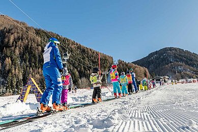 Kinder beim Skifahren in der Skischule im Familienhotel Huber in Südtirol.