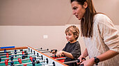 Mutter und Sohn spielen Tischkicker im Familienhotel Alpenhof Dolomit Family