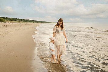 Mutter und Tochter genießen den Spaziergang am strand des Familienhotesl Seeklause an der Ostsee.