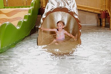 Ein Kind rutscht die Rutsche im Schwimmbad hinunter.