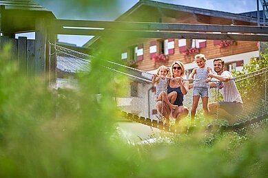 Eine Familie auf einer Hängebrücke auf dem Spielplatz im Familienhotel Amiamo im Salzburger Land