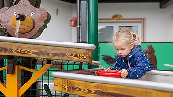 Mädchen planscht auf dem Wasserspielplatz vom Kaiserhof in Berwang