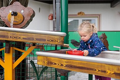 Mädchen planscht auf dem Wasserspielplatz vom Kaiserhof in Berwang