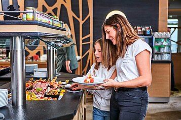 Mutter und Tochter bedienen sich am Buffet im Restaurant des Familienhotels Aigo welcome family in Oberösterreich