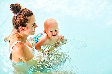 Mutter mit Baby im Schwimmbecken im Familienhotel Aigo welcome family in Oberösterreich